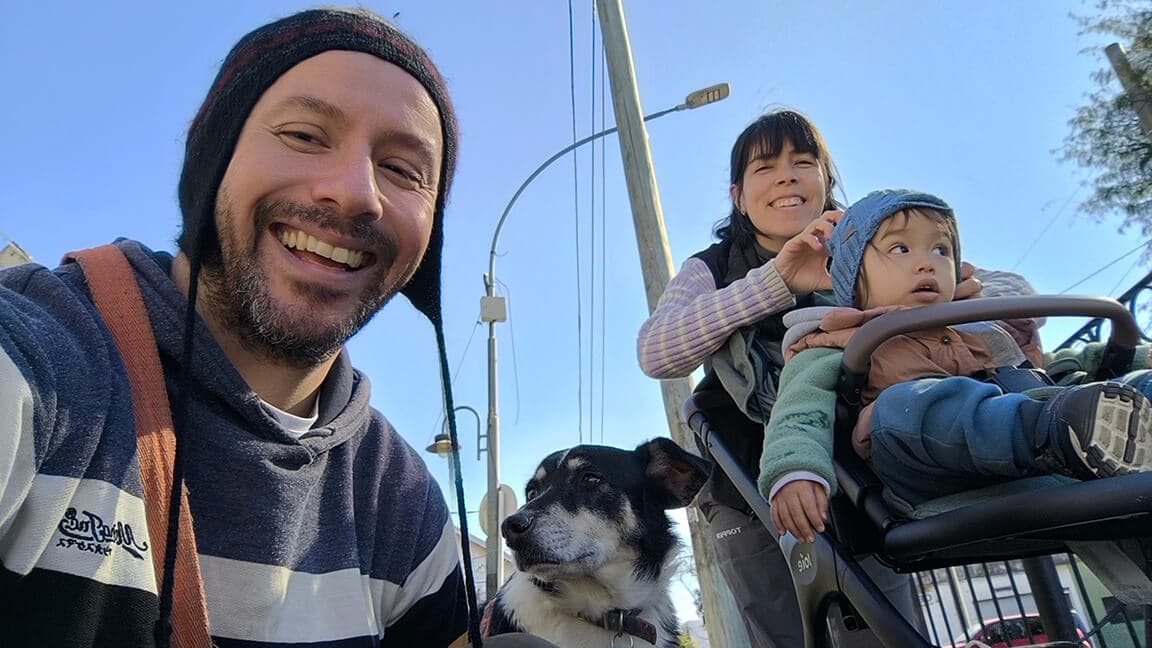 Rober con gorro de lana y Andre con Dante en el cochecito, Zama al lado, en la vereda de su barrio